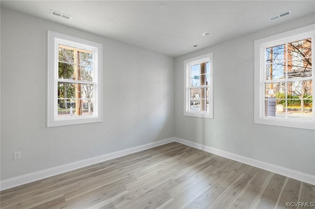 spare room featuring light hardwood / wood-style floors and a healthy amount of sunlight