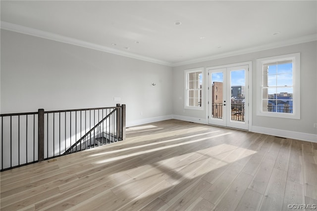 unfurnished room with ornamental molding, light wood-type flooring, and french doors