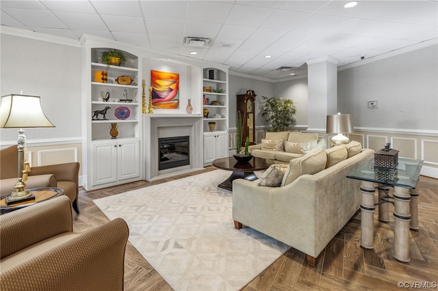 living room with crown molding, parquet floors, and built in shelves