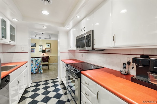 kitchen featuring appliances with stainless steel finishes, tasteful backsplash, light tile flooring, and white cabinets