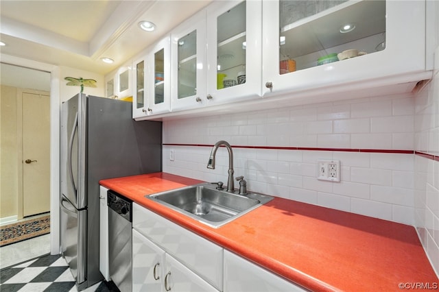 kitchen featuring white cabinets, tile floors, stainless steel dishwasher, a raised ceiling, and tasteful backsplash