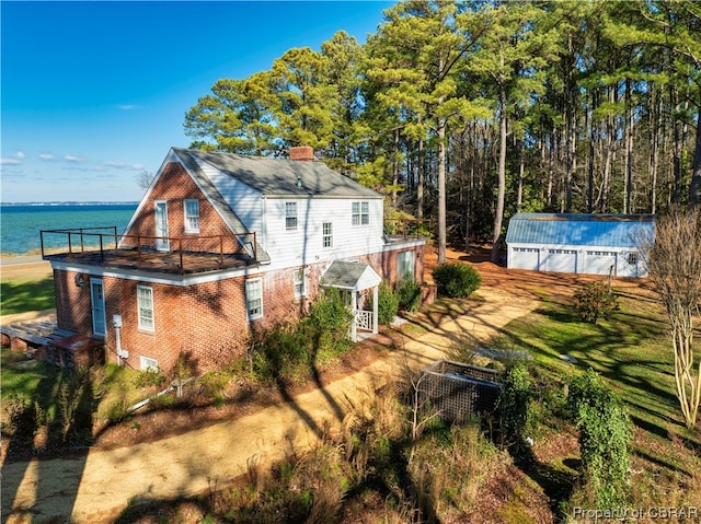 rear view of house with an outdoor structure and a water view