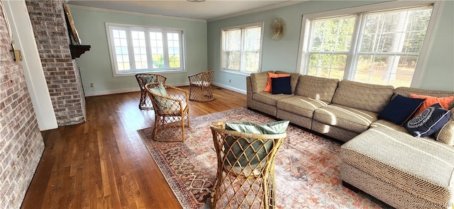 living room with brick wall, a healthy amount of sunlight, ornamental molding, and dark wood-type flooring