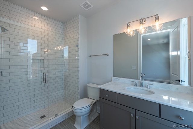 bathroom featuring a shower with shower door, vanity, tile patterned flooring, and toilet