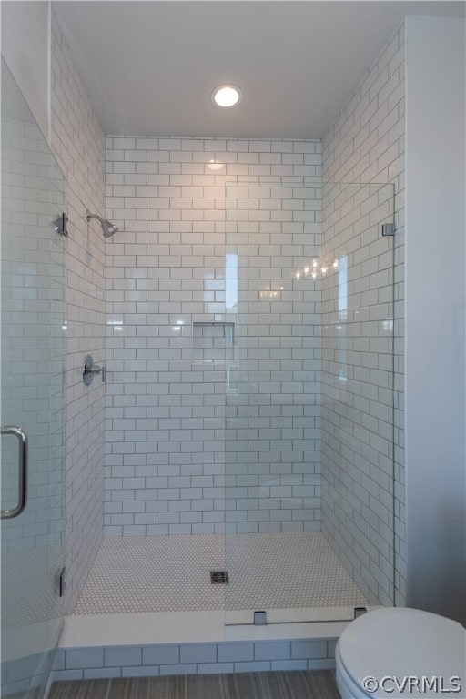 bathroom featuring a shower with door and toilet