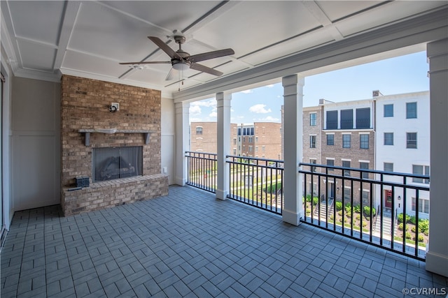 interior space with a balcony, ceiling fan, and a brick fireplace