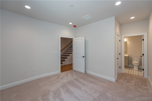 unfurnished bedroom with light carpet and ensuite bath