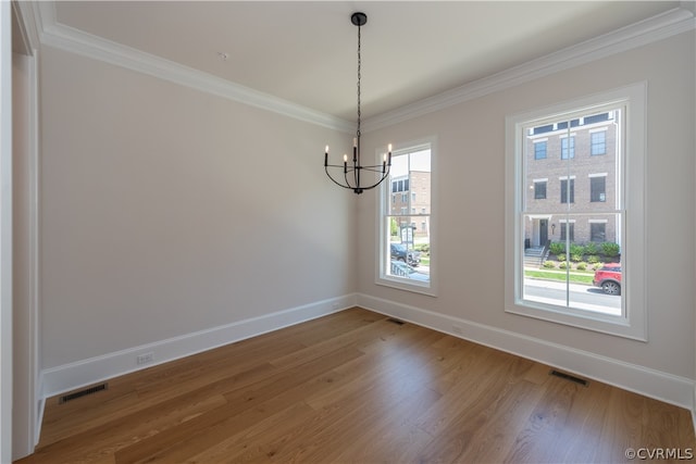 unfurnished dining area featuring an inviting chandelier, hardwood / wood-style flooring, and crown molding