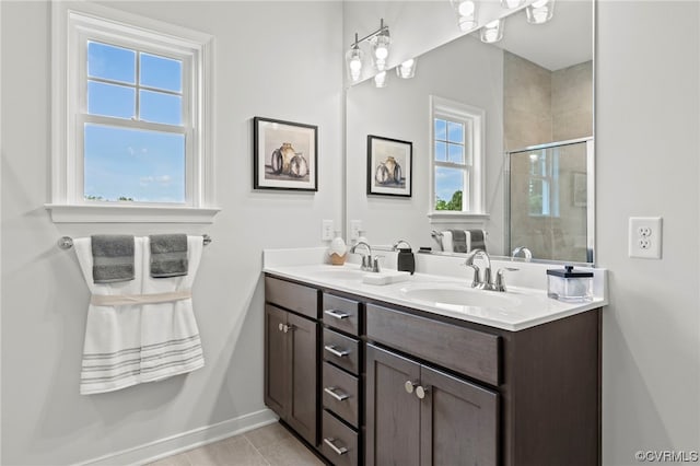 bathroom with dual vanity, tile flooring, and a healthy amount of sunlight