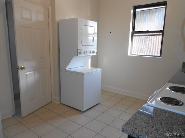 clothes washing area featuring light tile flooring and stacked washing maching and dryer