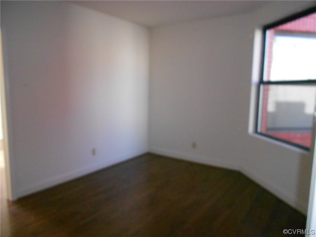 unfurnished room with dark wood-type flooring