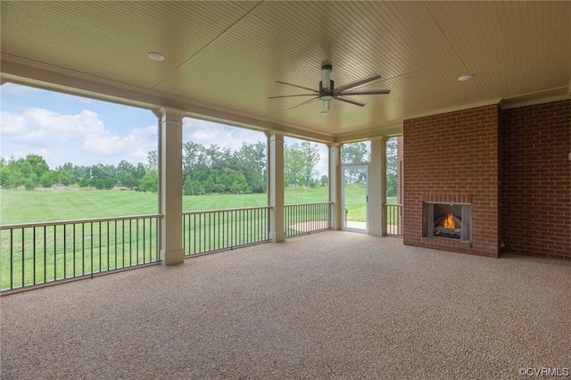 unfurnished sunroom with an outdoor brick fireplace and ceiling fan