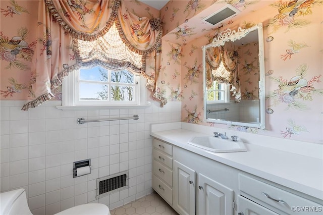 bathroom featuring plenty of natural light, toilet, vanity, and tile walls