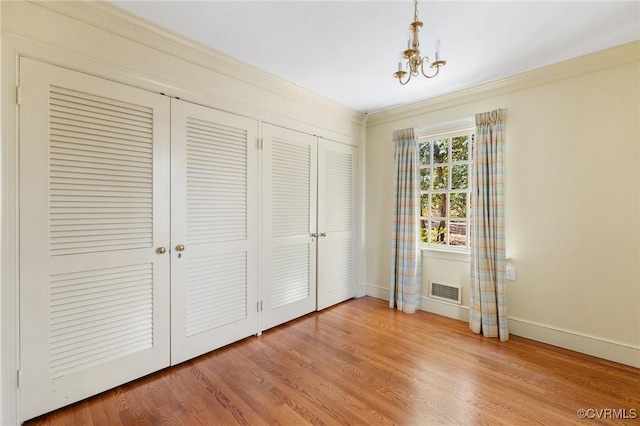 unfurnished bedroom with hardwood / wood-style flooring, ornamental molding, and a closet