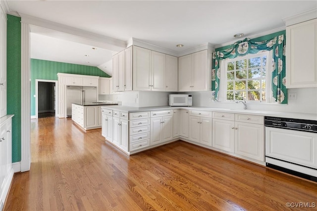 kitchen featuring white cabinetry, vaulted ceiling, dishwasher, and light hardwood / wood-style flooring