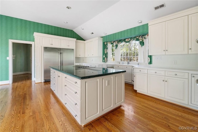 kitchen featuring lofted ceiling, white cabinetry, built in refrigerator, light hardwood / wood-style flooring, and a kitchen island