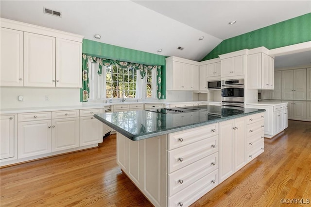 kitchen with a kitchen island, white cabinets, and light hardwood / wood-style flooring