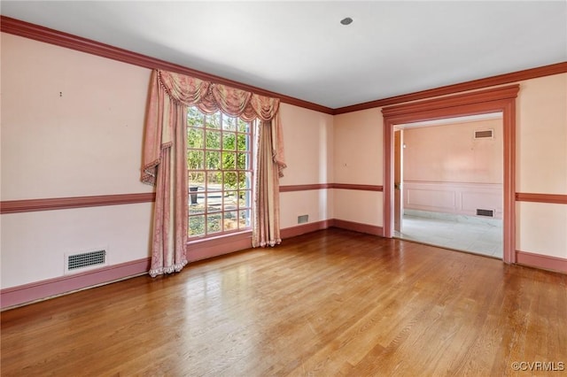 unfurnished room with ornamental molding and hardwood / wood-style floors