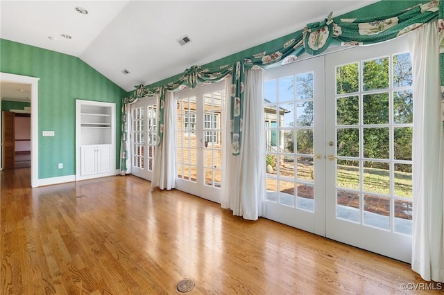 entryway with lofted ceiling, light wood-type flooring, and french doors