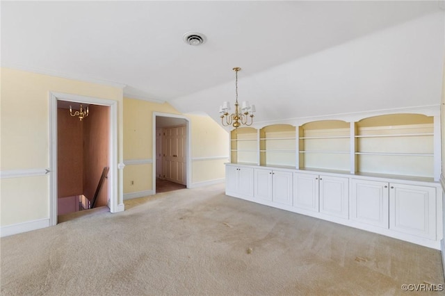 carpeted spare room featuring a chandelier and vaulted ceiling