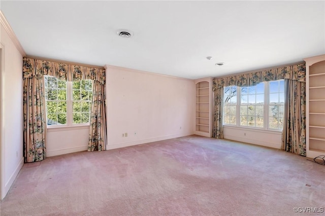 carpeted empty room featuring crown molding and built in features