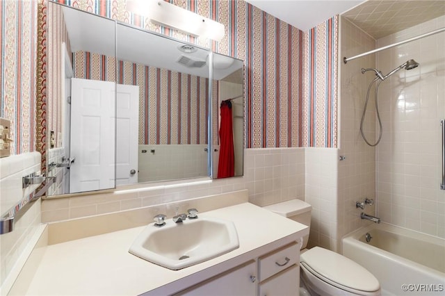 full bathroom with tile walls, backsplash, tiled shower / bath combo, vanity, and toilet