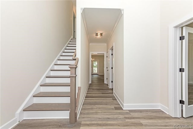 stairs featuring light wood-type flooring and crown molding