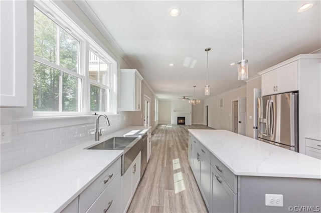 kitchen featuring light hardwood / wood-style floors, stainless steel fridge, tasteful backsplash, a kitchen island, and sink