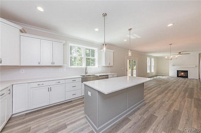 kitchen with light hardwood / wood-style floors, white cabinets, backsplash, and a large fireplace