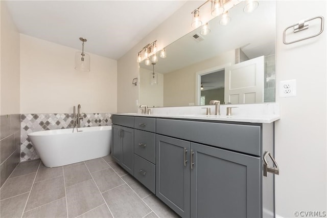 bathroom with tile walls, oversized vanity, dual sinks, ceiling fan, and tile flooring