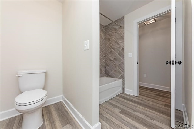 bathroom featuring hardwood / wood-style flooring, toilet, and tiled shower / bath combo