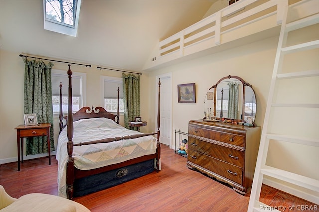 bedroom with wood-type flooring, high vaulted ceiling, and multiple windows