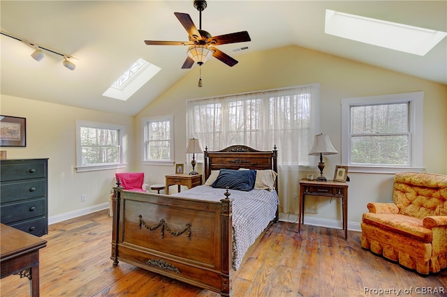 bedroom featuring ceiling fan, light hardwood / wood-style flooring, and lofted ceiling with skylight