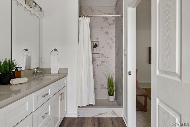 bathroom featuring wood-type flooring, walk in shower, and vanity