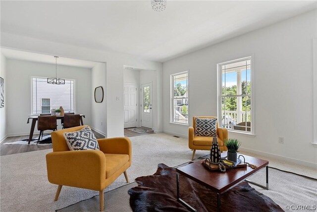 carpeted living room with a notable chandelier