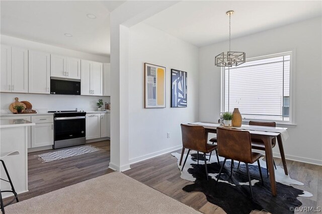 dining room with dark hardwood / wood-style floors and an inviting chandelier