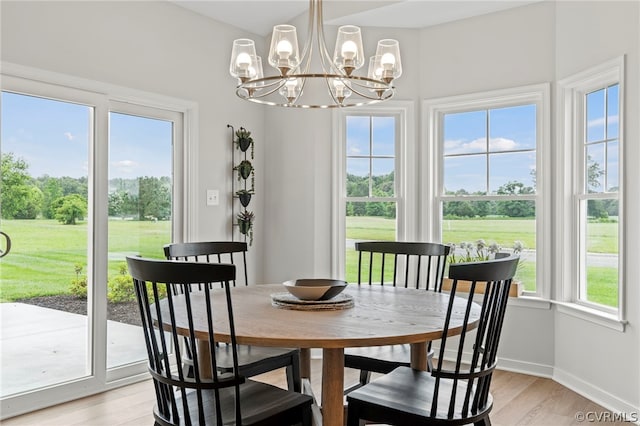 dining space with a wealth of natural light, light hardwood / wood-style floors, and a notable chandelier