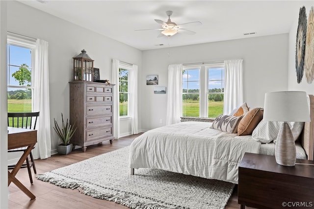 bedroom with hardwood / wood-style flooring, ceiling fan, and multiple windows