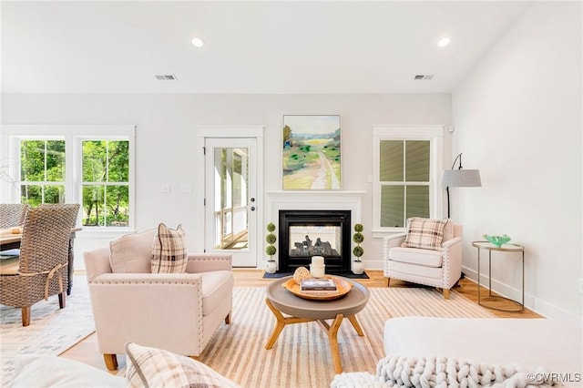 living area with recessed lighting, a multi sided fireplace, light wood-style flooring, and baseboards