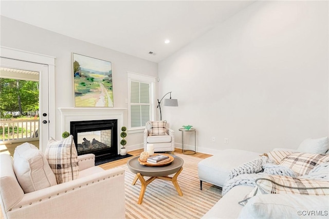 living room featuring wood finished floors, a multi sided fireplace, baseboards, and recessed lighting