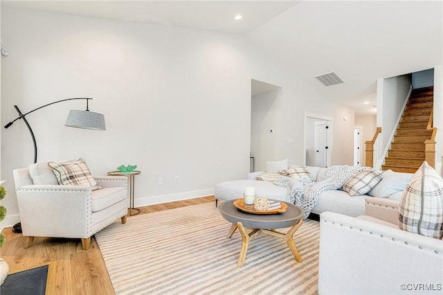 living room with light wood finished floors, lofted ceiling, stairway, and baseboards