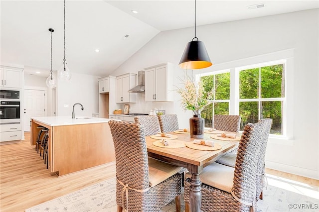 dining room with light wood-style floors, vaulted ceiling, and recessed lighting