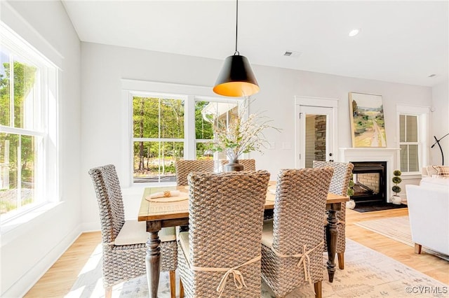 dining room featuring light wood-style floors, a fireplace, and baseboards