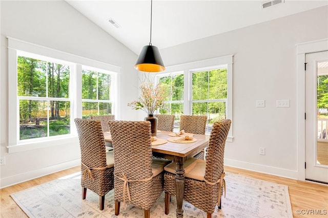 dining room with vaulted ceiling, baseboards, and light wood-type flooring