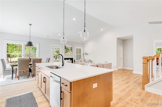 kitchen featuring a sink, dishwashing machine, light wood-style floors, lofted ceiling, and light countertops