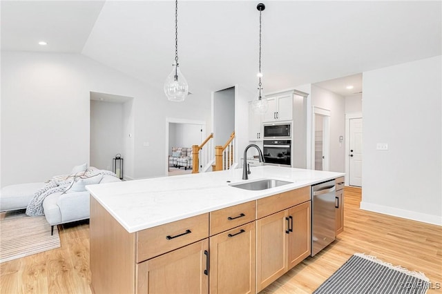 kitchen featuring a sink, stainless steel dishwasher, built in microwave, black oven, and light wood-style flooring