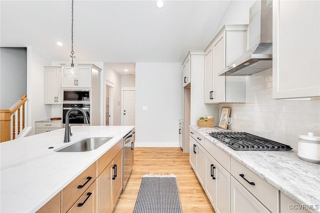 kitchen with wall chimney exhaust hood, a sink, appliances with stainless steel finishes, backsplash, and recessed lighting