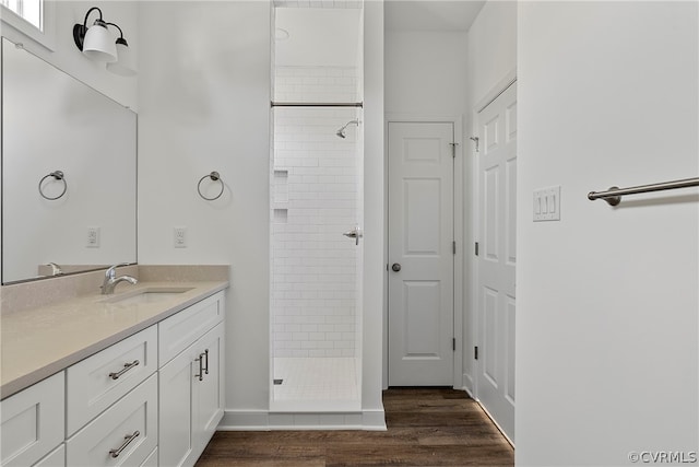 bathroom featuring tiled shower, hardwood / wood-style floors, and vanity