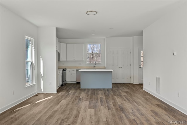 kitchen with white cabinets, stove, a center island, and wood-type flooring