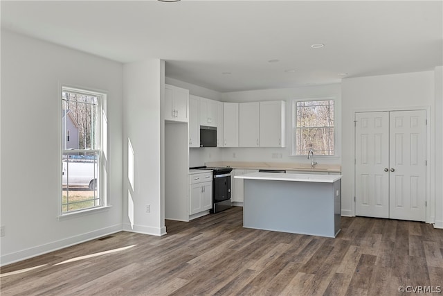 kitchen with a kitchen island, white cabinetry, appliances with stainless steel finishes, and dark wood-type flooring